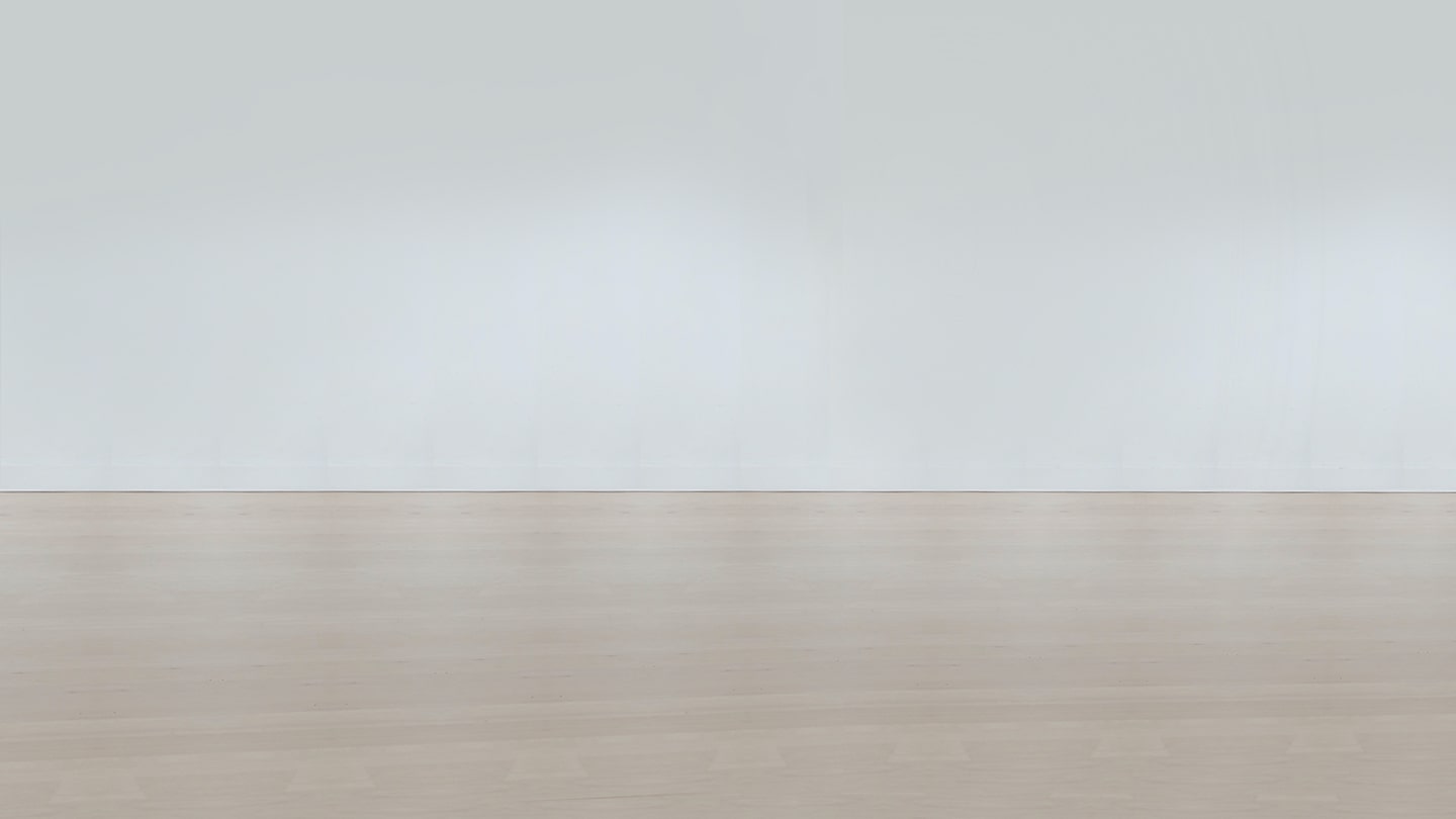 A blank white wall with beige hardwood floors