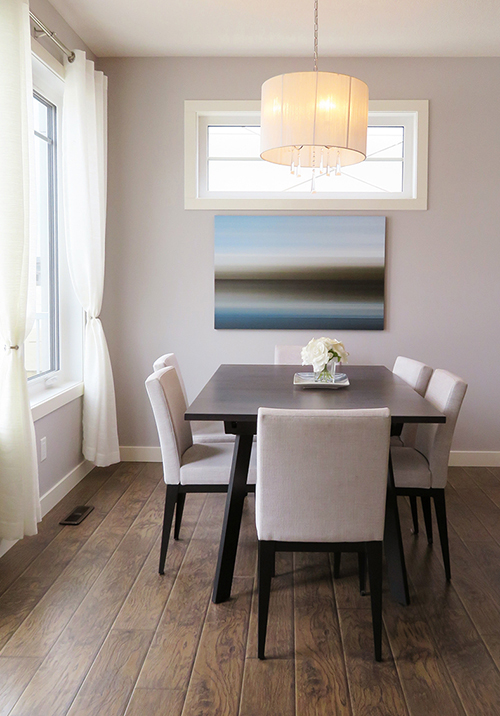 A dining room staged with tables, chairs, artwork, and assorted furniture.